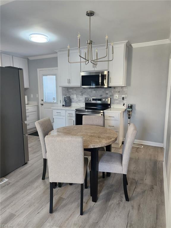 dining area with crown molding, an inviting chandelier, and light wood-type flooring