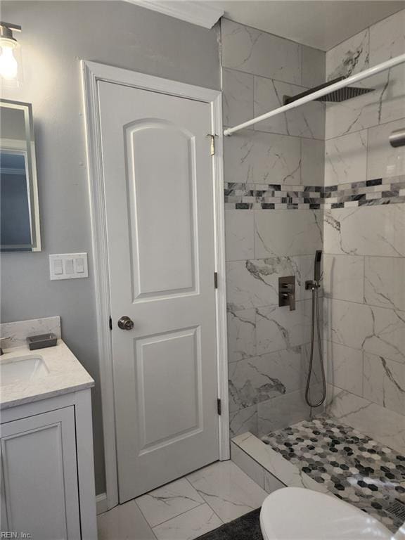 bathroom with tiled shower, vanity, and toilet