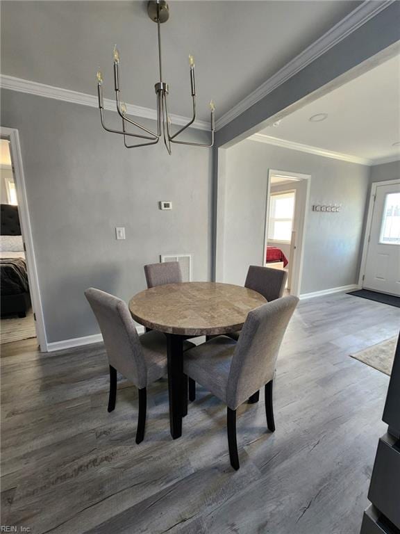 dining space featuring ornamental molding, dark wood-type flooring, and a notable chandelier