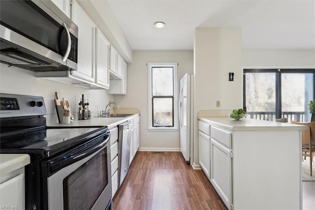 kitchen with dark wood-type flooring, appliances with stainless steel finishes, sink, and white cabinets