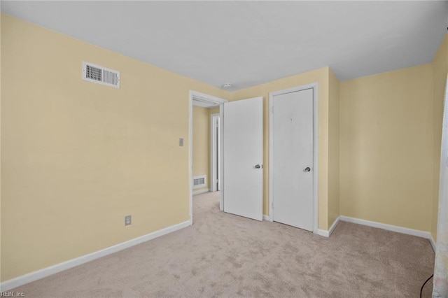 unfurnished bedroom featuring light colored carpet and a closet