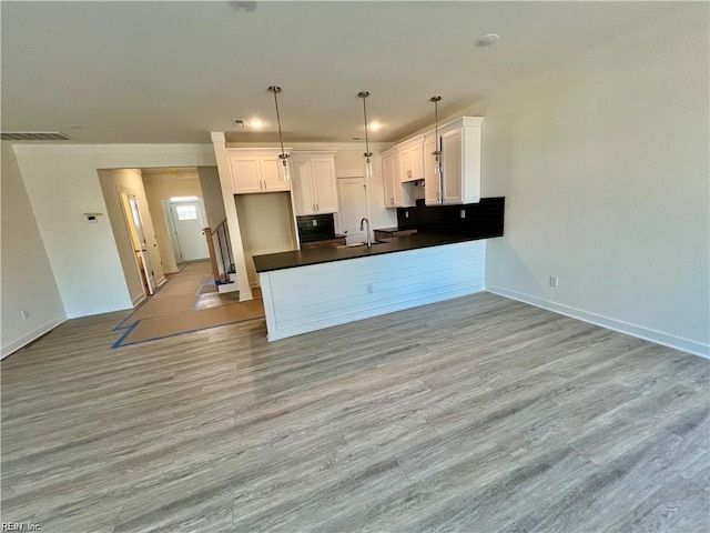 kitchen featuring hanging light fixtures, white cabinetry, sink, and light hardwood / wood-style floors