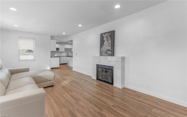 living room featuring a tiled fireplace and light hardwood / wood-style floors