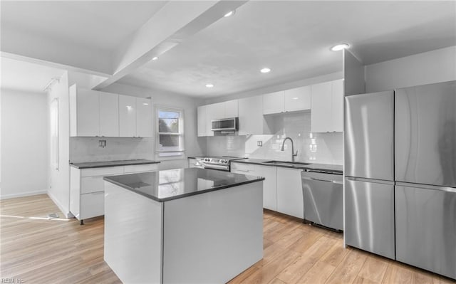 kitchen with sink, light wood-type flooring, appliances with stainless steel finishes, a kitchen island, and white cabinets