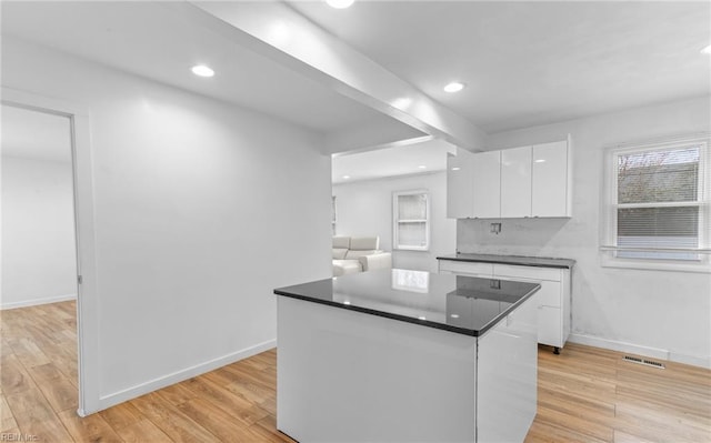 kitchen with a center island, white cabinets, and light wood-type flooring