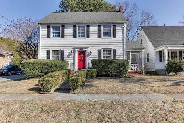 colonial-style house featuring a front yard and a sunroom