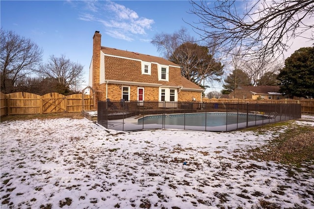 snow covered house featuring a fenced in pool