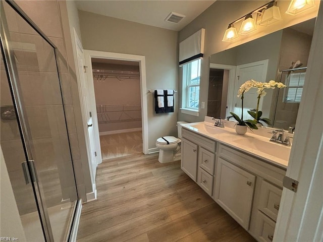 bathroom featuring hardwood / wood-style flooring, vanity, toilet, and walk in shower