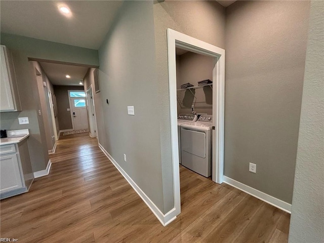 hall with washer and dryer and light hardwood / wood-style flooring