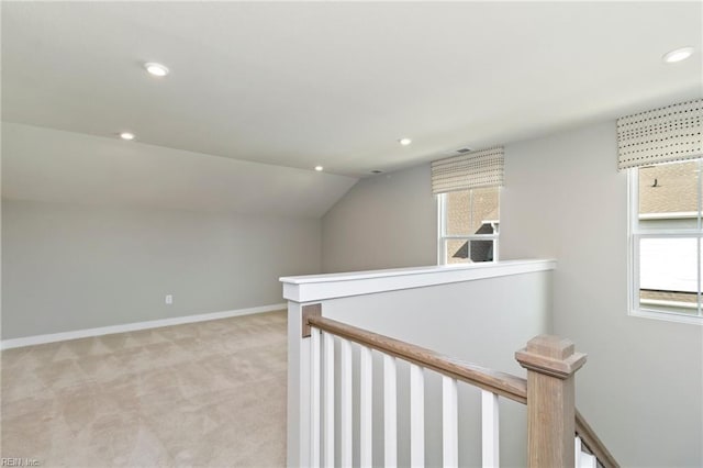 hallway featuring lofted ceiling and light colored carpet