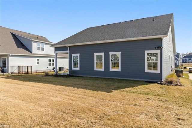 rear view of property with central air condition unit and a lawn