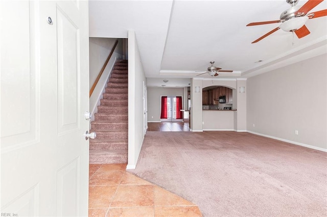 unfurnished living room featuring light carpet, ceiling fan, and a tray ceiling