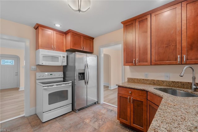 kitchen with sink, white appliances, and light stone countertops