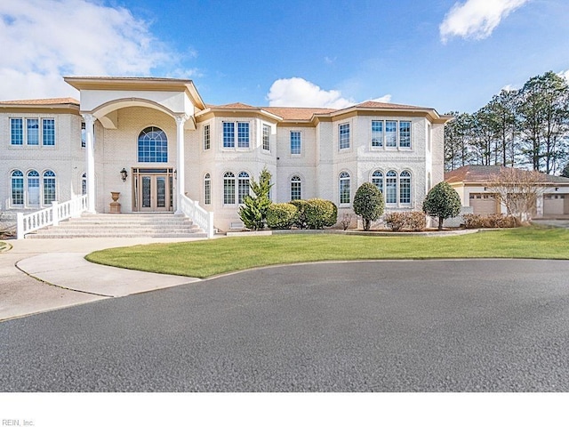 mediterranean / spanish-style home featuring a garage, a front lawn, and french doors