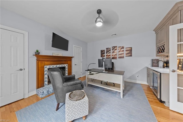 office space featuring sink, wine cooler, ceiling fan, and light hardwood / wood-style flooring