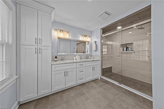 bathroom with a shower with door, vanity, and decorative backsplash