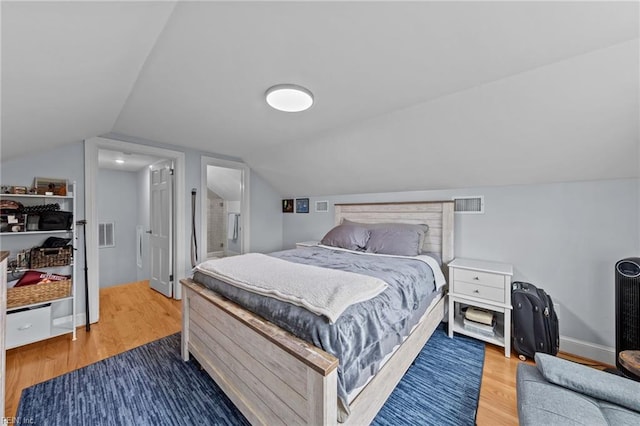 bedroom featuring connected bathroom, vaulted ceiling, and wood-type flooring