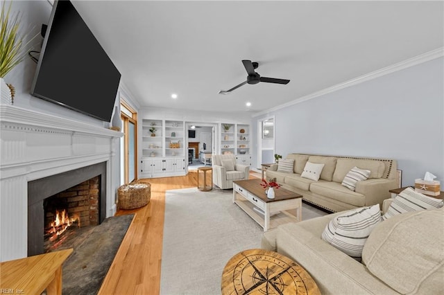 living room with wood-type flooring, ornamental molding, built in features, and ceiling fan