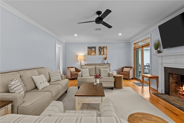 living room with ornamental molding, ceiling fan, and light wood-type flooring