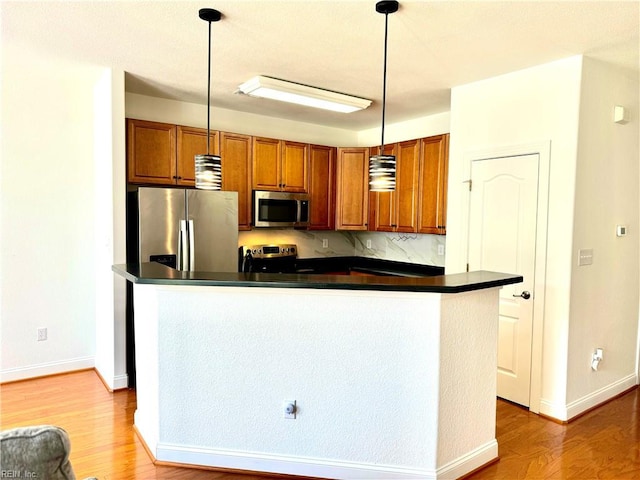 kitchen with decorative light fixtures, light hardwood / wood-style flooring, a center island, and appliances with stainless steel finishes