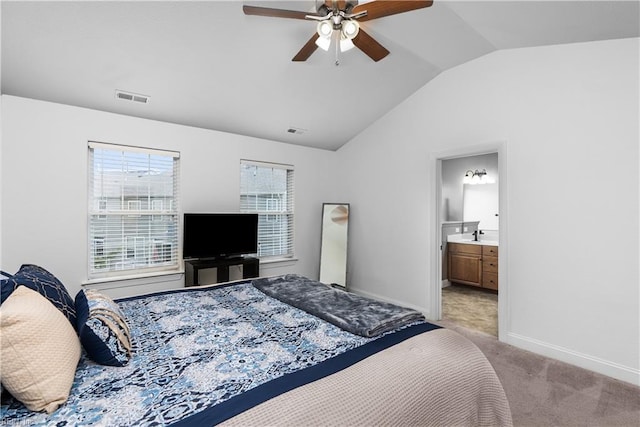 bedroom with vaulted ceiling, light colored carpet, ceiling fan, and ensuite bath