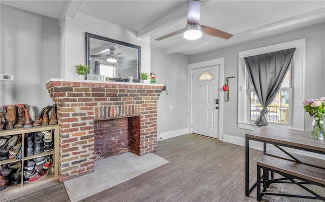 foyer entrance featuring ceiling fan, beam ceiling, hardwood / wood-style floors, and a brick fireplace