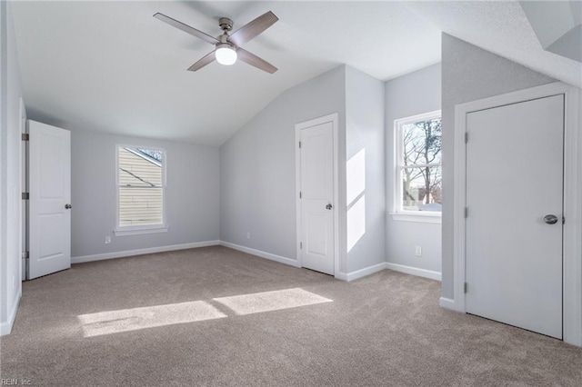 unfurnished bedroom featuring ceiling fan, lofted ceiling, and light colored carpet