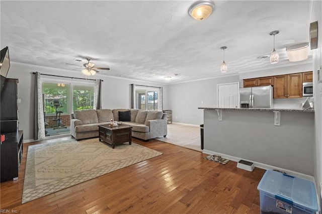 living room featuring ceiling fan, ornamental molding, and light hardwood / wood-style floors