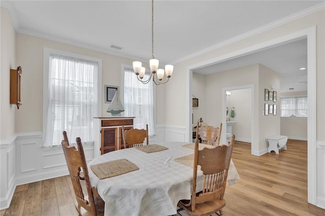 dining area featuring ornamental molding, light hardwood / wood-style flooring, and a notable chandelier