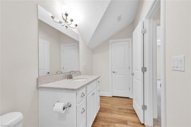 bathroom featuring lofted ceiling, toilet, a textured ceiling, vanity, and hardwood / wood-style flooring