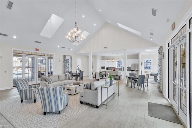 living room with a notable chandelier, a skylight, high vaulted ceiling, and french doors