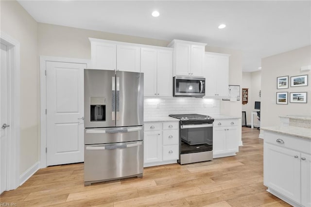 kitchen featuring stainless steel appliances, white cabinetry, backsplash, and light hardwood / wood-style flooring