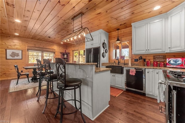 kitchen with appliances with stainless steel finishes, white cabinetry, light stone countertops, a kitchen bar, and decorative light fixtures