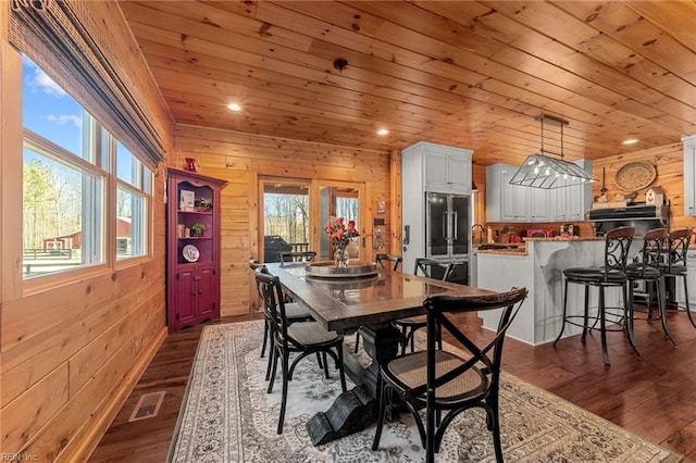 dining room with wooden ceiling, dark hardwood / wood-style flooring, a wealth of natural light, and wood walls