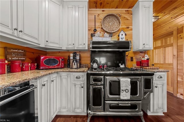 kitchen with white cabinetry, wooden walls, black dishwasher, and light stone counters