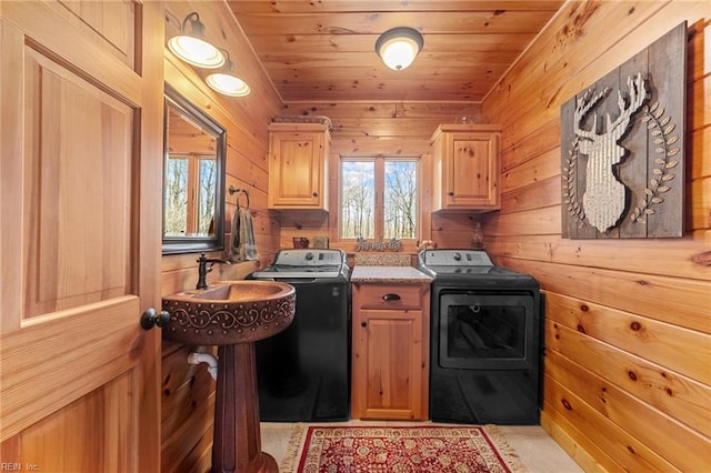 washroom featuring wood walls, sink, cabinets, washing machine and clothes dryer, and wooden ceiling