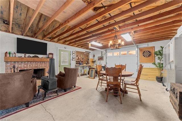 dining space featuring concrete flooring, a chandelier, and a wood stove