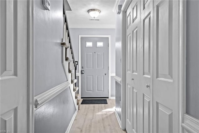 doorway with crown molding and light wood-type flooring