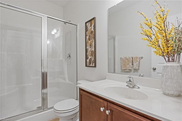 bathroom with vanity, a shower with door, and toilet