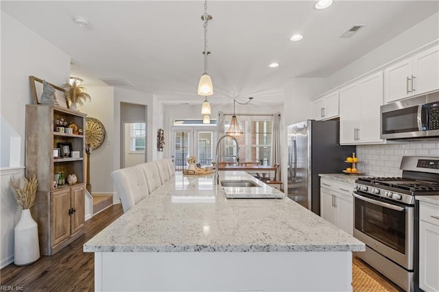 kitchen featuring stainless steel appliances, a kitchen island with sink, and white cabinets