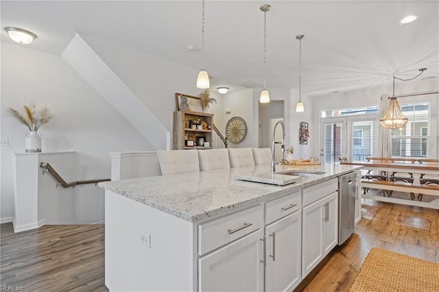 kitchen featuring white cabinetry, sink, a center island with sink, and decorative light fixtures