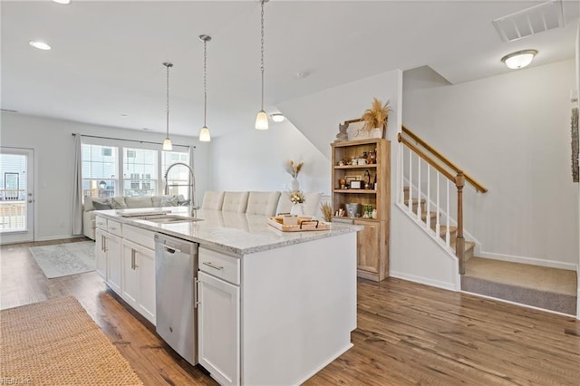 kitchen with white cabinetry, sink, stainless steel dishwasher, and a center island with sink