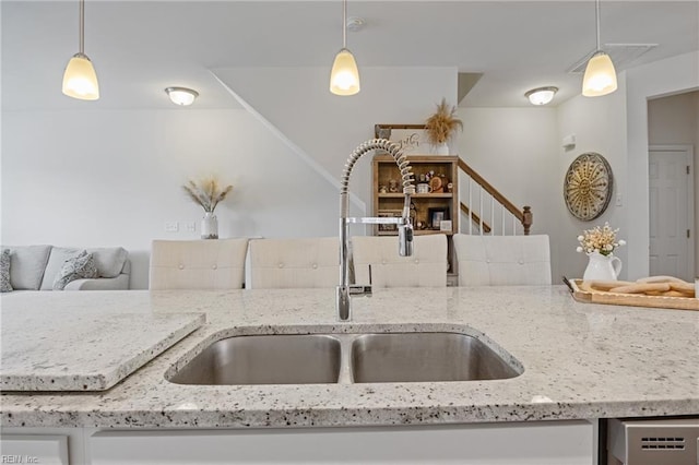 kitchen featuring light stone counters, sink, and decorative light fixtures