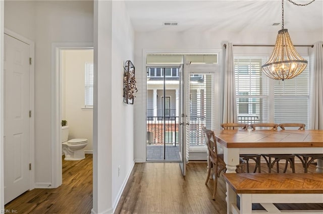 dining space featuring wood-type flooring and a notable chandelier