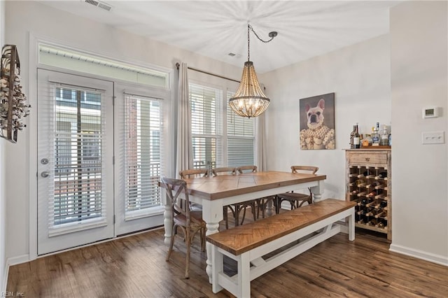 dining area featuring dark wood-type flooring and a notable chandelier