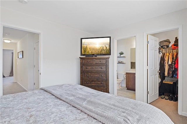 carpeted bedroom with a walk in closet, ensuite bath, and a closet