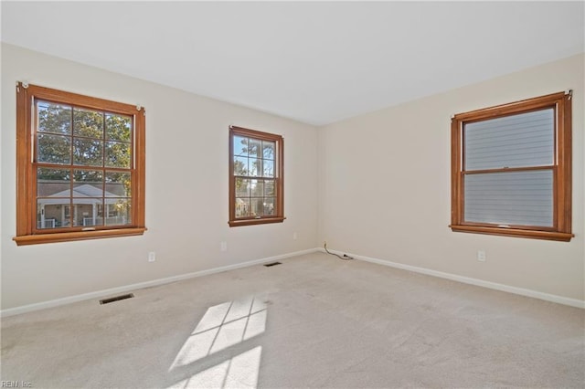 unfurnished room with a wealth of natural light and light colored carpet