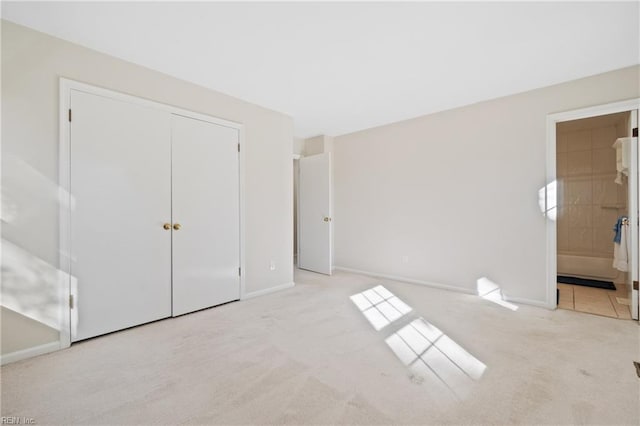 unfurnished bedroom with connected bathroom, light colored carpet, and a closet