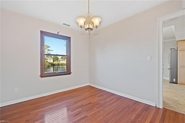 unfurnished room with an inviting chandelier and light hardwood / wood-style flooring