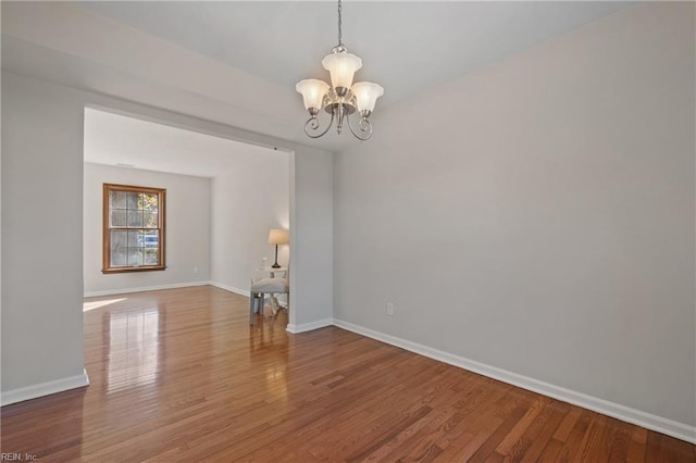 unfurnished room with hardwood / wood-style flooring and a notable chandelier